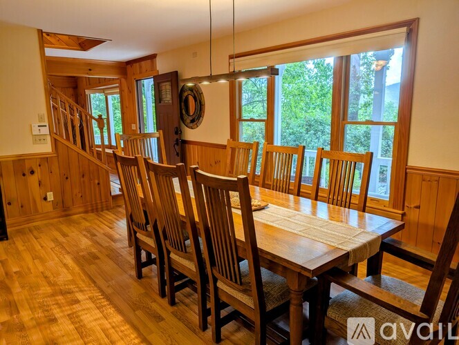 A wooden dining room with a long table and chairs.