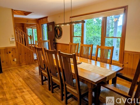 A wooden dining room with a long table and chairs.