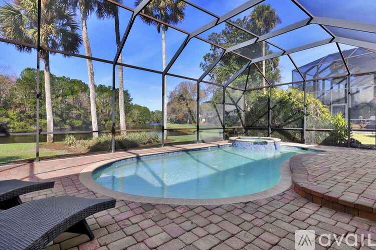 A pool surrounded by a glass enclosure with trees in the background.