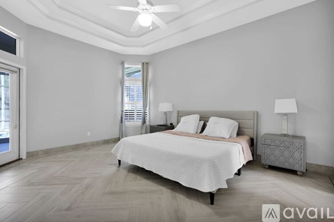 A bedroom with a large bed, a ceiling fan, and a nightstand with a lamp.