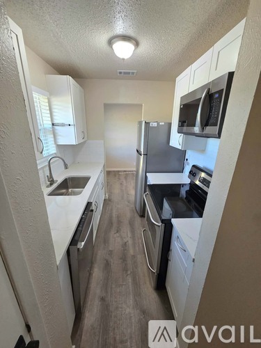 A small kitchen with white cabinets and a refrigerator.