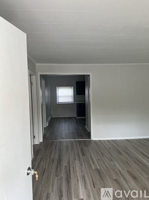 A room with a wooden floor and a door leading to another room.