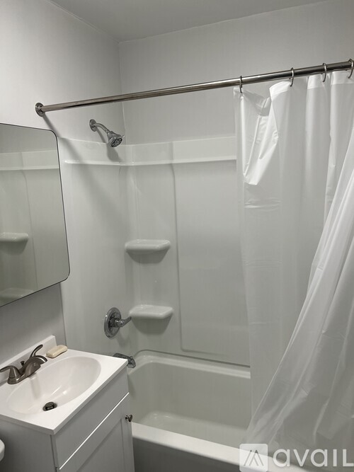 A white bathroom with a sink, mirror, and shower.