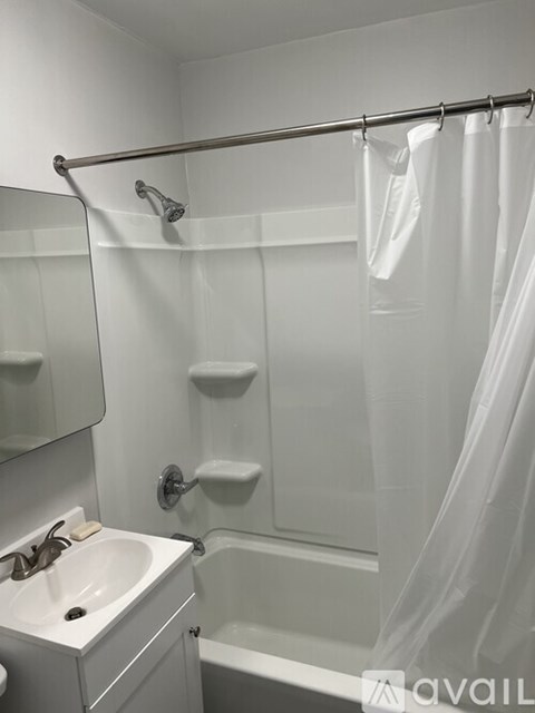 A white bathroom with a sink, mirror, and shower.