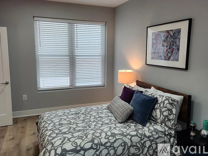 A bedroom with a patterned bedspread and a framed picture on the wall.