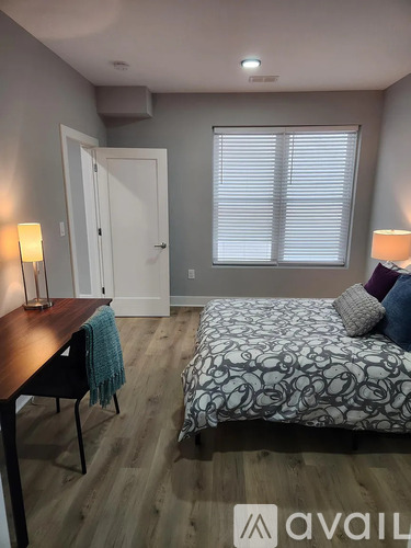 A bedroom with a bed, desk, and two lamps.