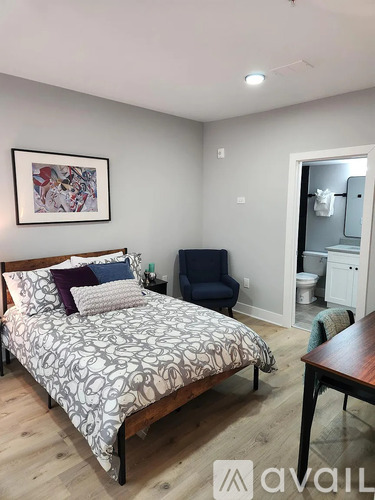 A bedroom with a bed, chair, and a painting on the wall.