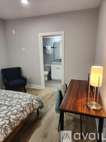A bedroom with a bed, chair, and table.