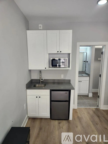 A kitchen with white cabinets and a black fridge.