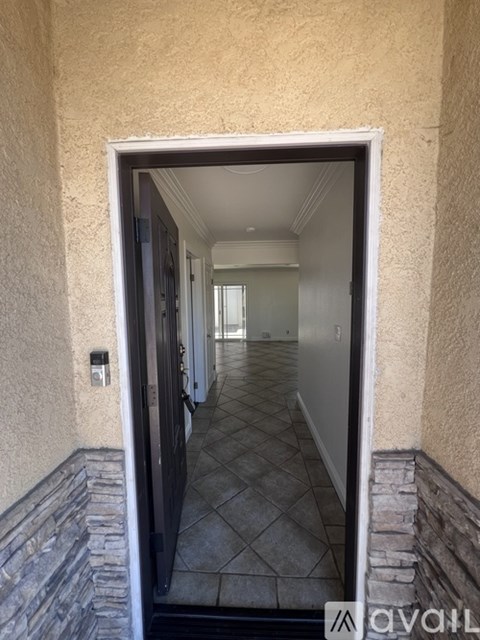 A hallway with a tiled floor and a stone ledge on the wall.