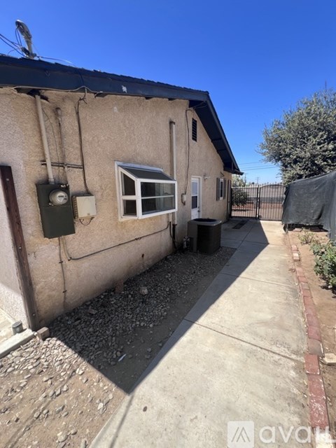 A small house with a brown stucco exterior and a black roof.