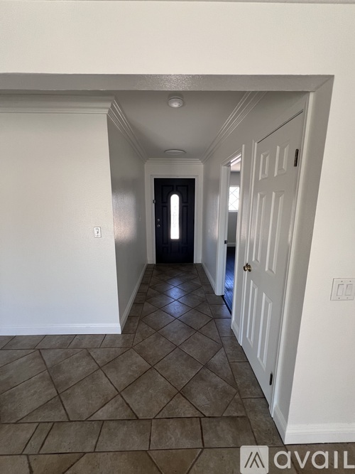 A hallway with a tiled floor and white walls.