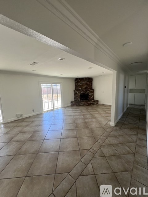 A spacious room with a fireplace and tiled flooring.