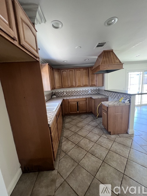 A kitchen with brown cabinets and a tile floor.