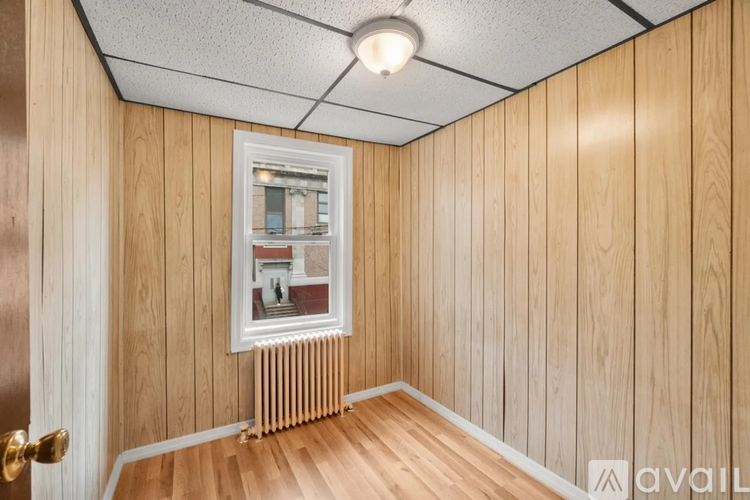 A room with wooden walls and a window showing a view of a building outside.