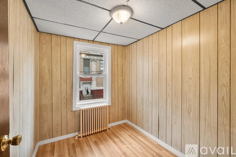 A room with wooden walls and a window showing a view of a building outside.