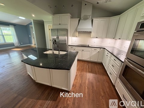 A kitchen with white cabinets and a black countertop.