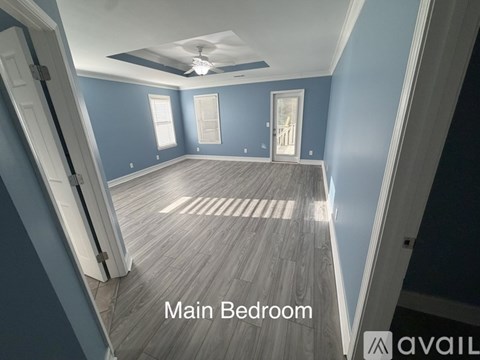 A main bedroom with a ceiling fan and wooden flooring.
