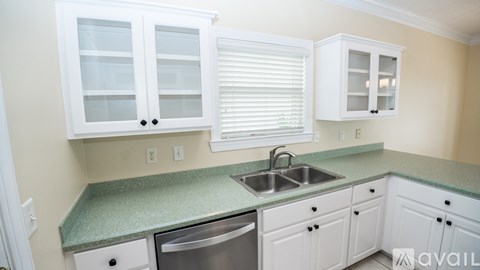 A kitchen with white cabinets and a green countertop.
