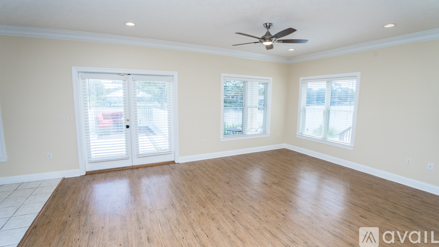 A spacious room with a ceiling fan and wooden flooring.