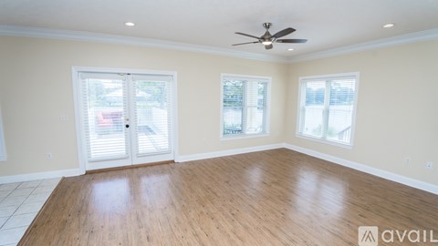 A spacious room with a ceiling fan and wooden flooring.