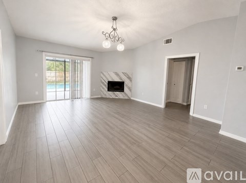 A spacious living room with a fireplace and a chandelier.
