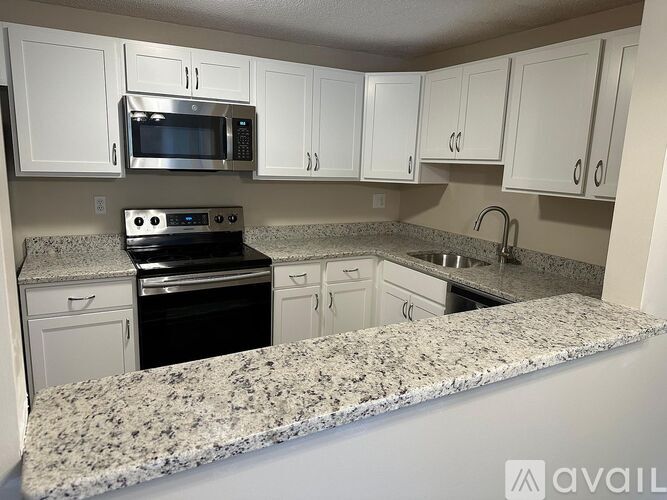 A kitchen with granite countertops and white cabinets.