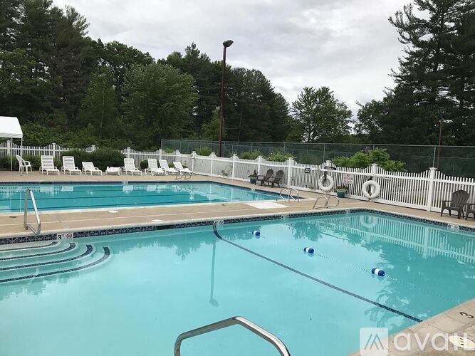 A pool with a white fence and trees in the background.