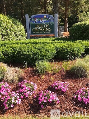 A sign that says Hollis Crossing stands in front of a neatly trimmed hedge.