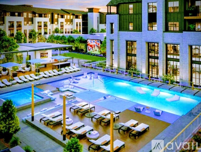 A large pool surrounded by lounge chairs and umbrellas in front of a modern building.