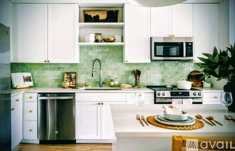 A kitchen with white cabinets and a green backsplash.