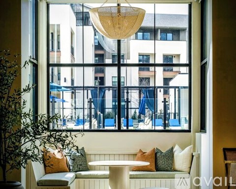 A living room with a large window overlooking a balcony with chairs and umbrellas.