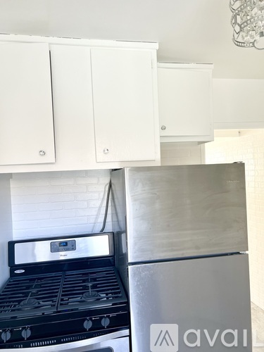 A white kitchen with a black stove and a silver fridge.