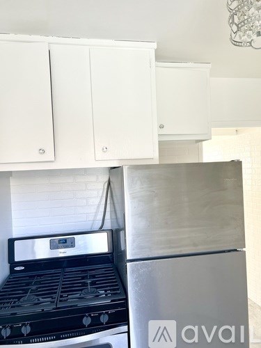 A white kitchen with a black stove and a silver fridge.