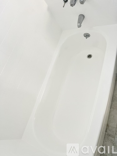 A white bathtub with a shower head and faucet.