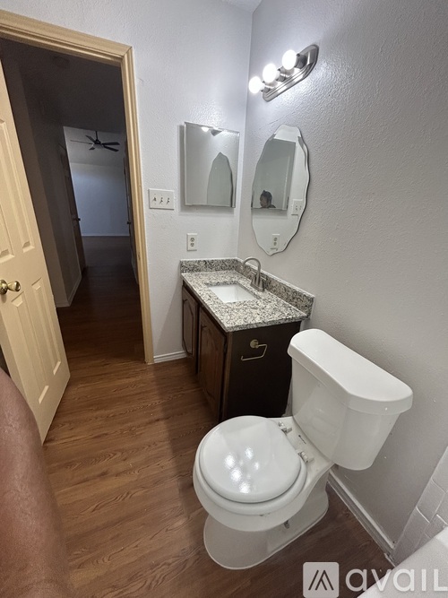 A white toilet with a white tank and a white sink with a granite counter top.
