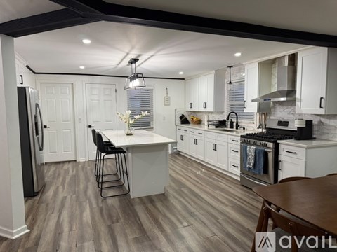 A kitchen with white cabinets and a wooden floor.