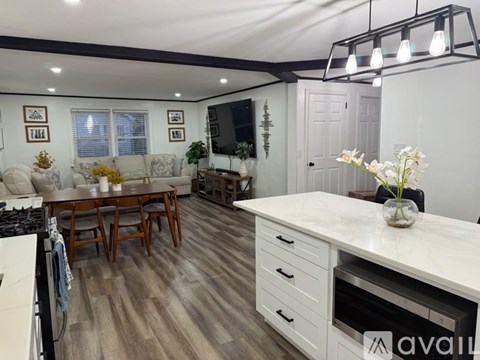 A kitchen with a white countertop and wooden flooring.