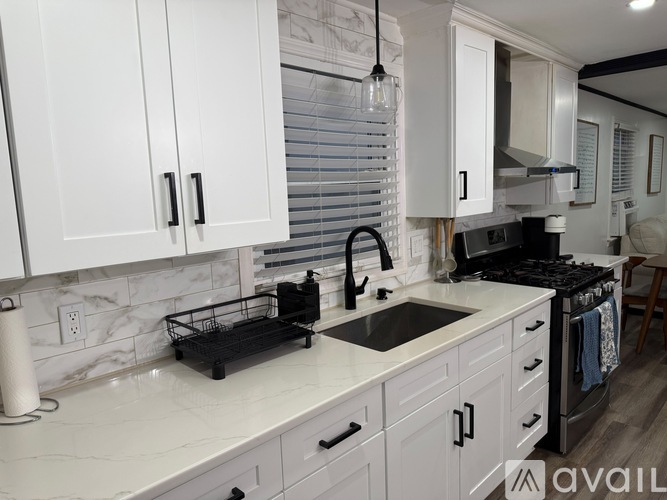 A kitchen with white cabinets and a marble backsplash.