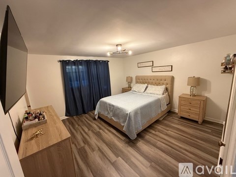 A bedroom with a bed, nightstand, and a wooden dresser.