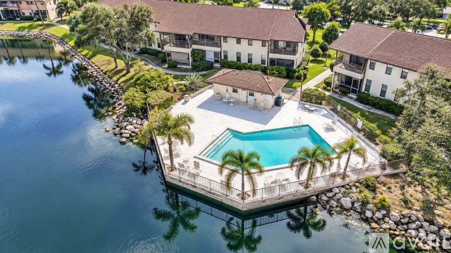 A house with a pool is surrounded by water and palm trees.