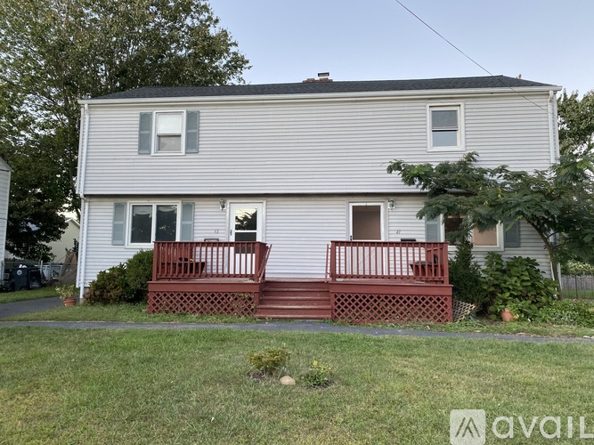 A house with a grey siding and a red deck.