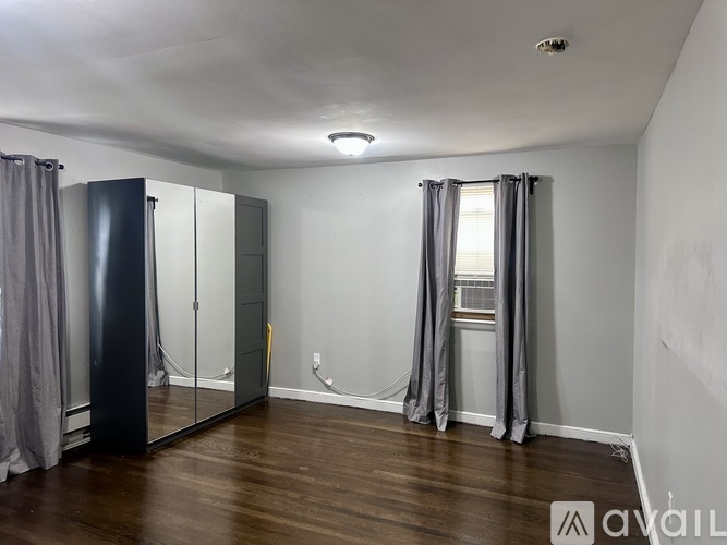 A bedroom with a large mirror and grey curtains.