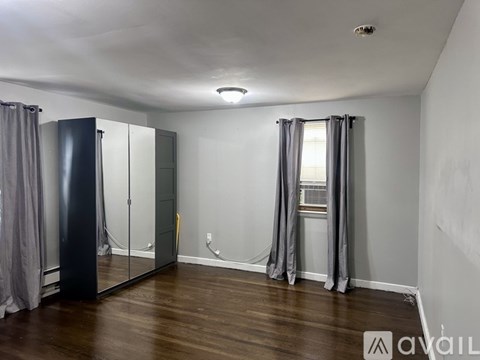 A bedroom with a large mirror and grey curtains.