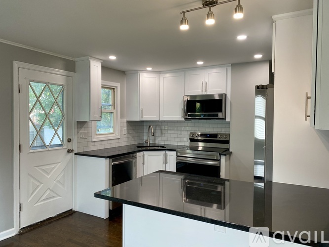 A kitchen with white cabinets and black countertops.