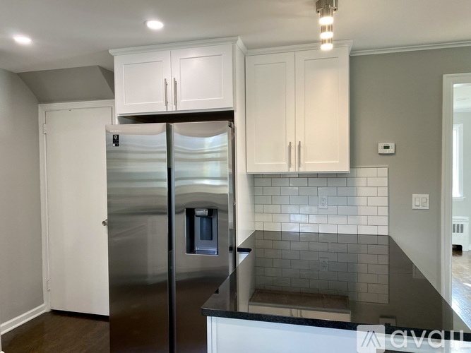 A kitchen with a stainless steel refrigerator and white cabinets.