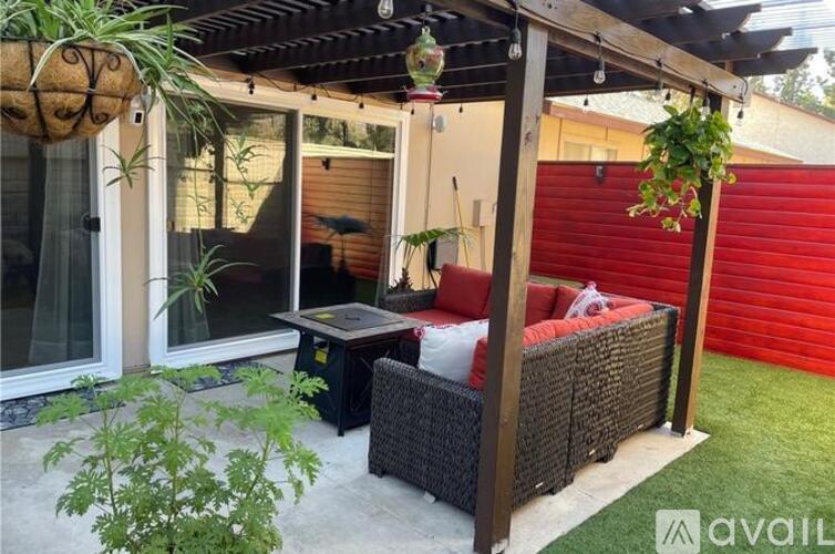 A patio with a red couch and a table under a pergola.
