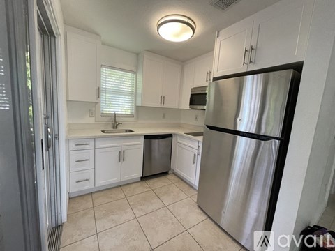 A kitchen with white cabinets and a stainless steel refrigerator.