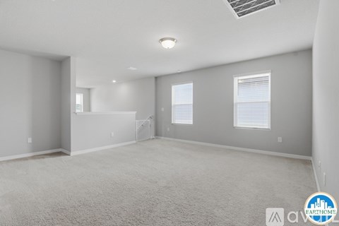 A spacious room with carpeted floor and a window with blinds.