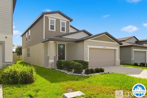 A modern house with a grey and white exterior and a green lawn in front.